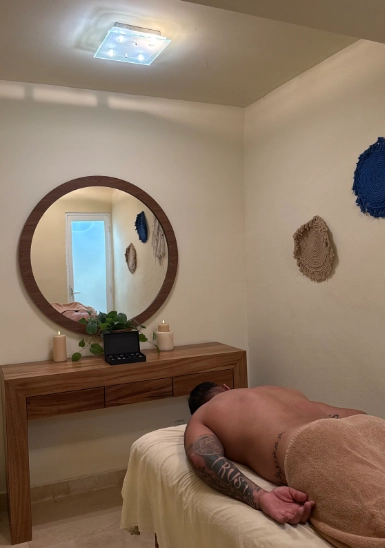 Man resting on bed in a cozy bedroom with wooden dresser and round mirror