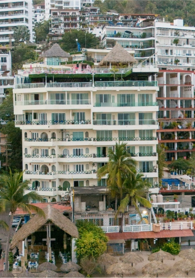 Tropical resort with white multi-story buildings and thatched roofs, palm trees