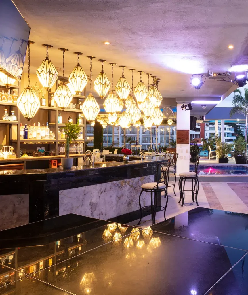 Modern bar lounge with hanging pendant lanterns and marble counters at dusk