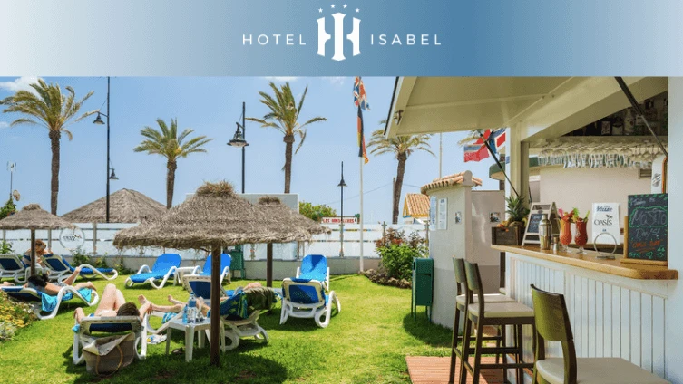 Jard&iacute;n del Hotel Isabel con palmeras, hamacas y barra bajo toldo.