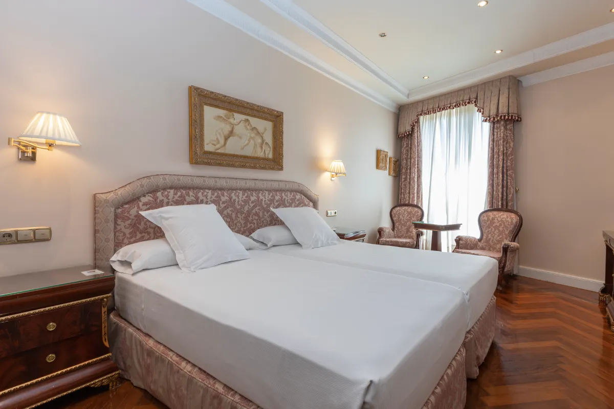 Dormitorio con cama doble, lámparas y cortinas junto a una ventana