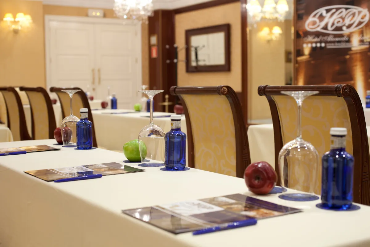 Mesa de conferencias con copas de colores y sillas en salón interior