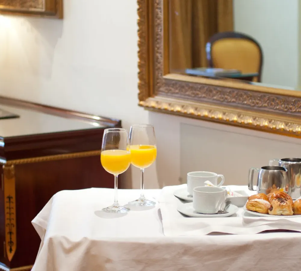 Mesa de desayuno en hotel con dos copas de jugo naranja y boller&iacute;a