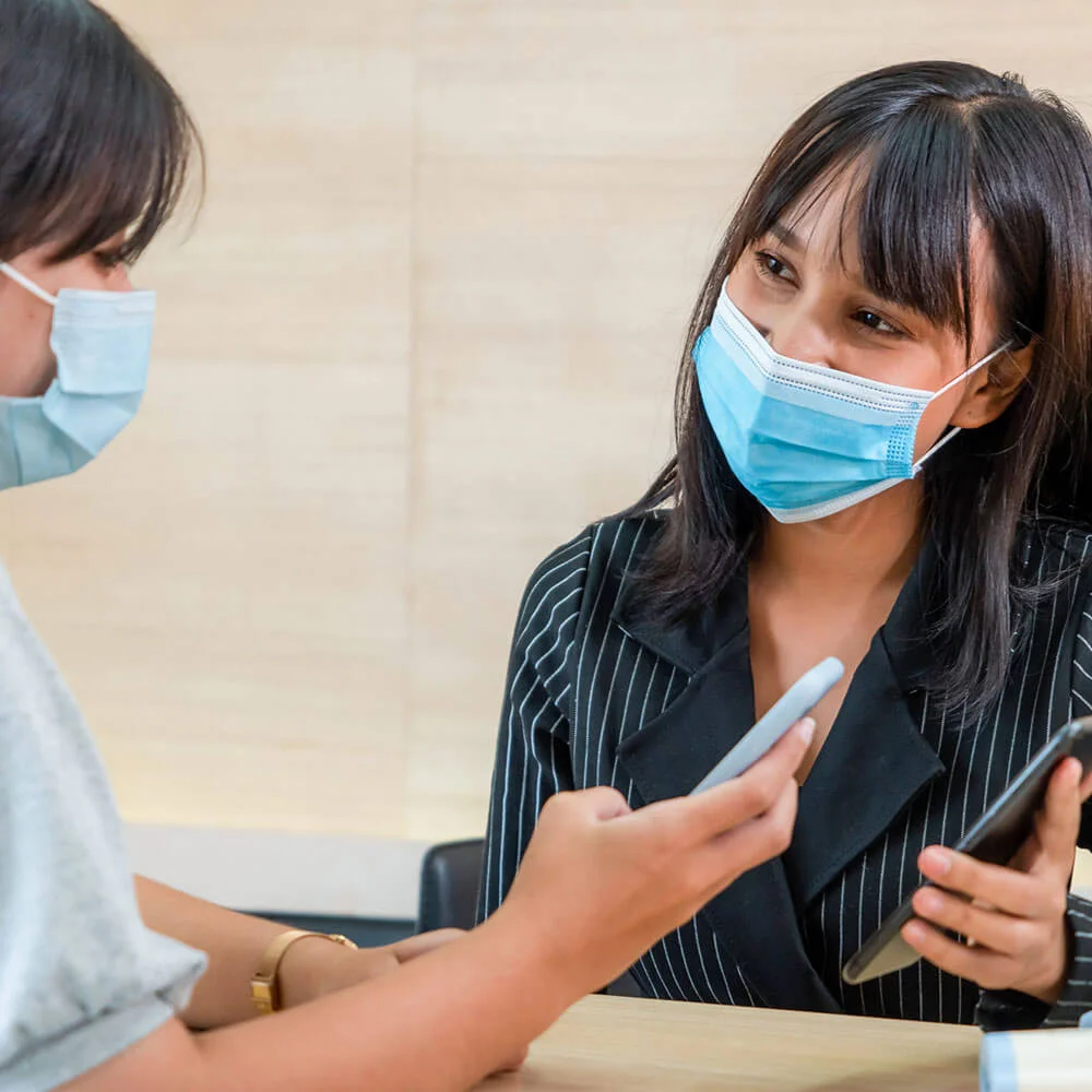 Mujer con mascarilla habla en consulta m&eacute;dica con paciente en primer plano