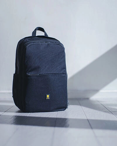 Mochila azul oscura en el suelo, con luz y sombra en interior.