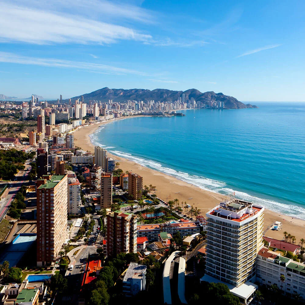 Vista a&eacute;rea de una ciudad costera con playas y rascacielos junto al mar azul