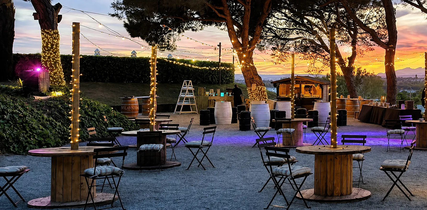 Terraza de eventos con luces colgantes y mesas, al atardecer