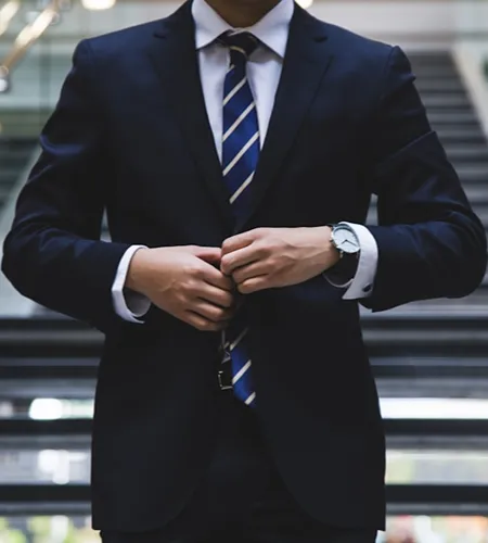 Hombre con traje oscuro y corbata, ajust&aacute;ndose la chaqueta