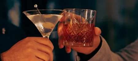 C&oacute;cteles en vasos con hielo, una mano sostiene los tragos.