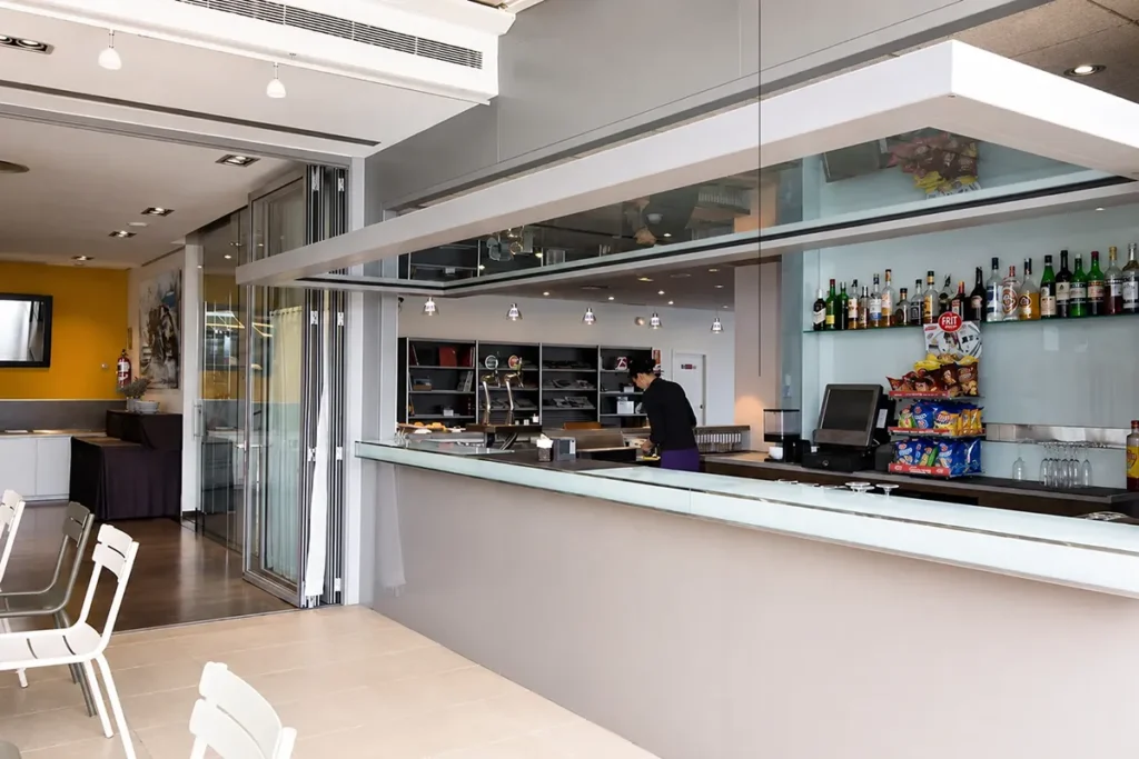 Bar moderno con barra de bebidas, luces colgantes y sillas blancas en interior