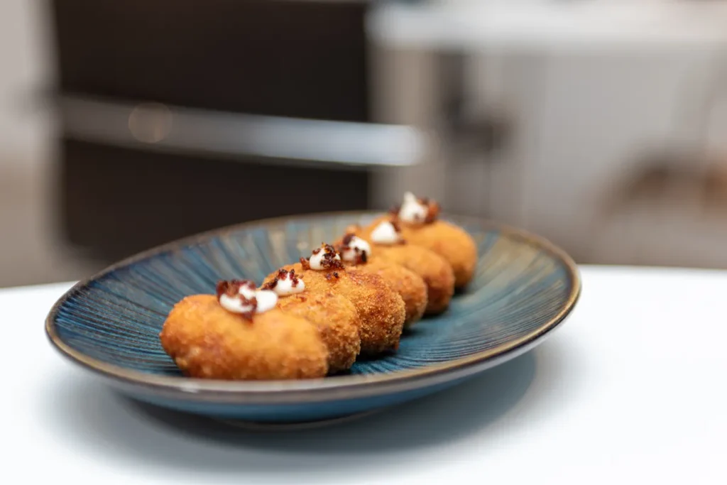Croquetas de arroz con crema y semillas de s&eacute;samo en un plato azul