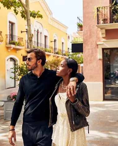 Pareja paseando en un pueblo con casas coloridas al sol
