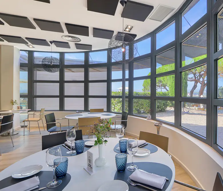 Mesa servida con copas y decoraci&oacute;n azul, sala moderna con ventanas panor&aacute;micas