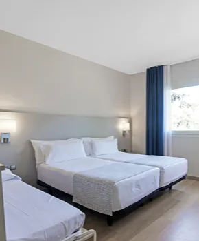 Dormitorio moderno con dos camas y cabecero blanco en tonos neutros.