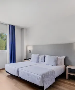 Habitaci&oacute;n de hotel con cama doble y almohadas, vista interior.