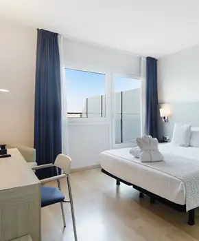 Habitaci&oacute;n moderna con cama, cortinas azules y ventanas con luz natural