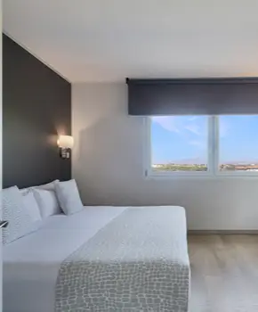 Dormitorio moderno con cama blanca y ventana con vista exterior