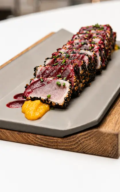 Trozos de sushi con salsa y s&eacute;samo sobre plato blanco y madera