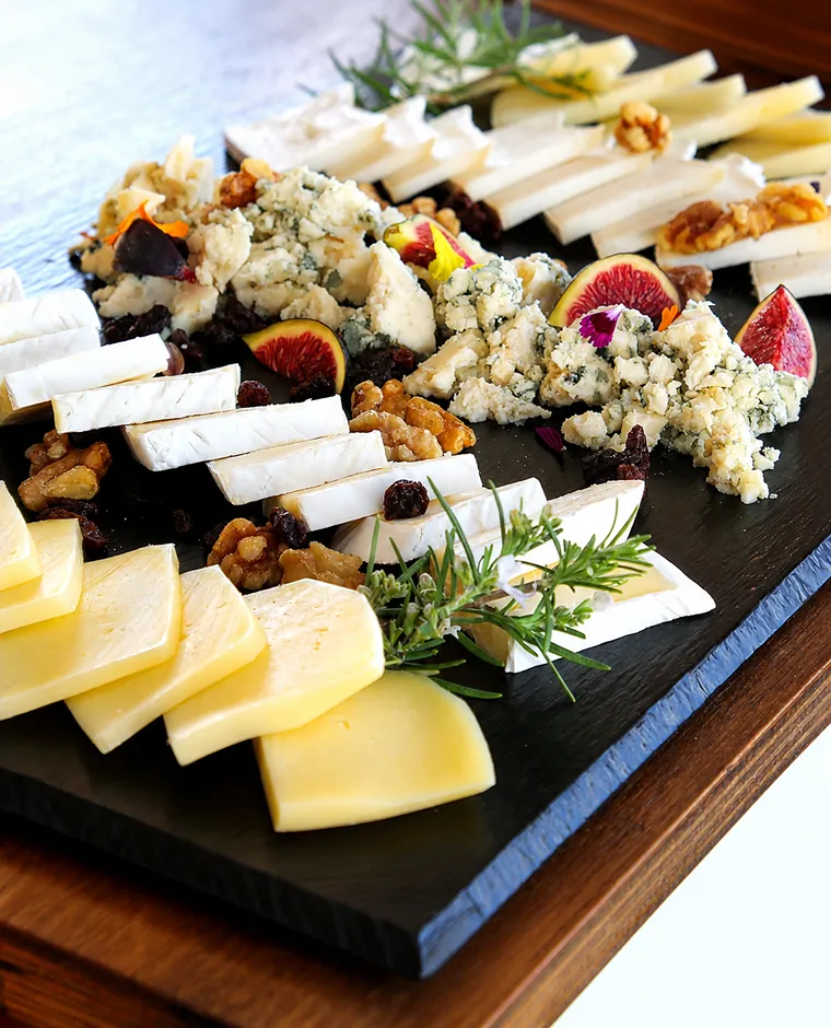 Tabla de quesos con higos, nueces y crumble, sobre pizarra negra