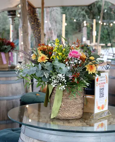 Arreglo floral multicolor en mesa de evento al aire libre, con decoraci&oacute;n