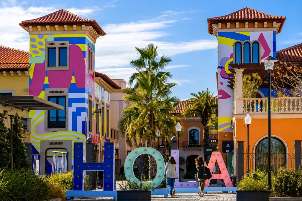 Fachada colorida con letras gigantes y palmeras en un edificio soleado