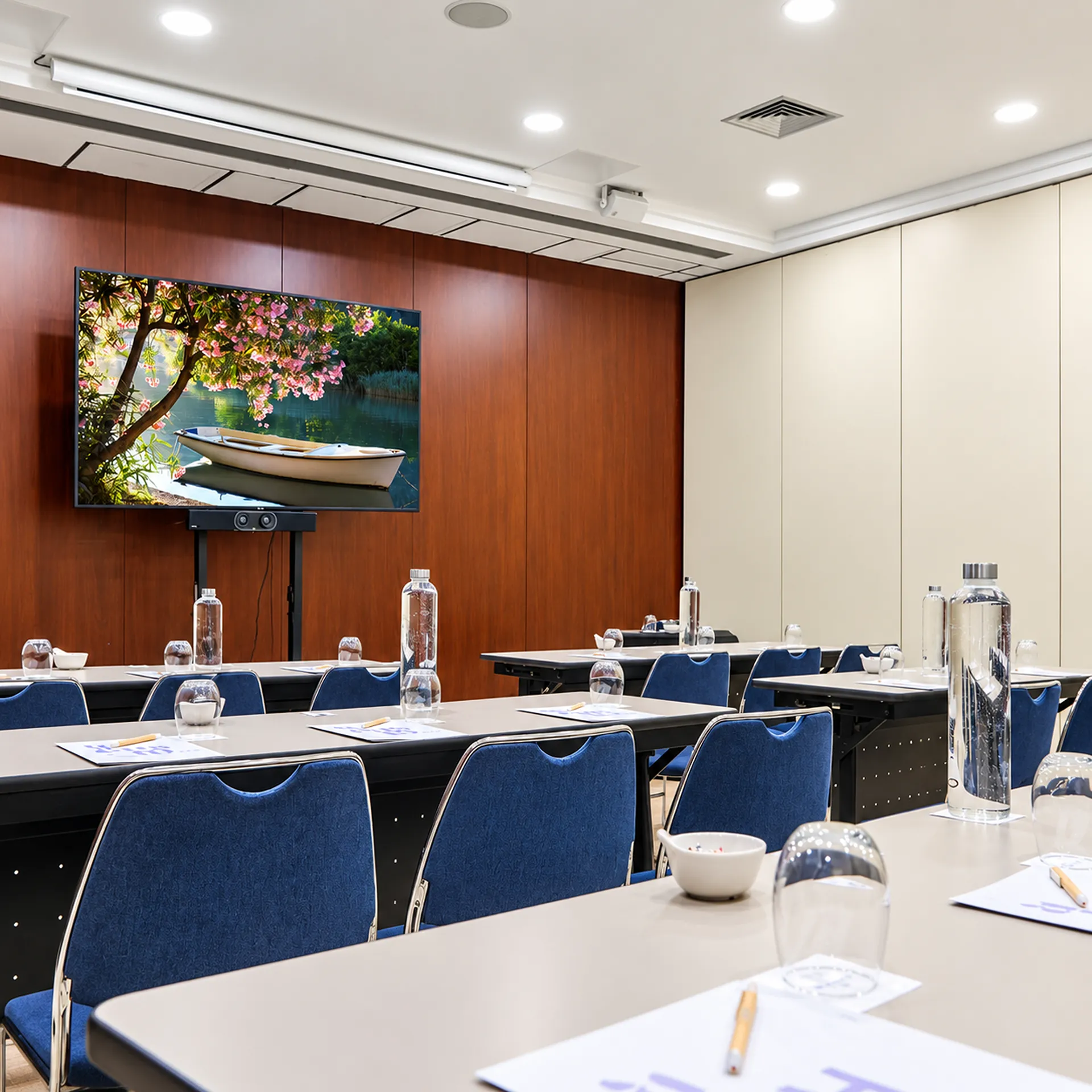 Sala de reuniones con televisores, mesas y luces LED en el techo