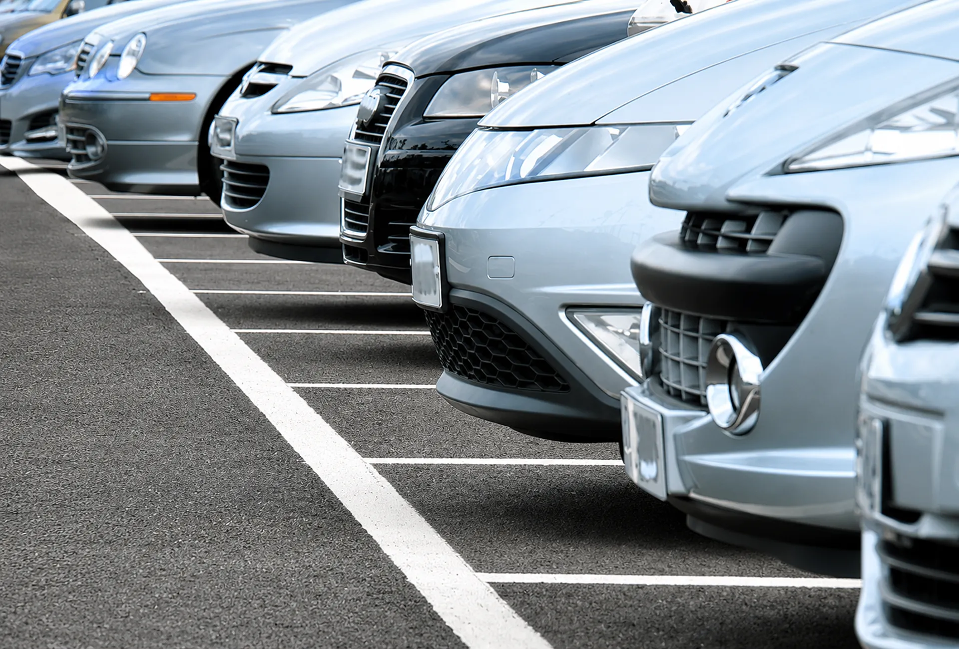 Primer plano de autos grises estacionados en fila, vista frontal y parrillas