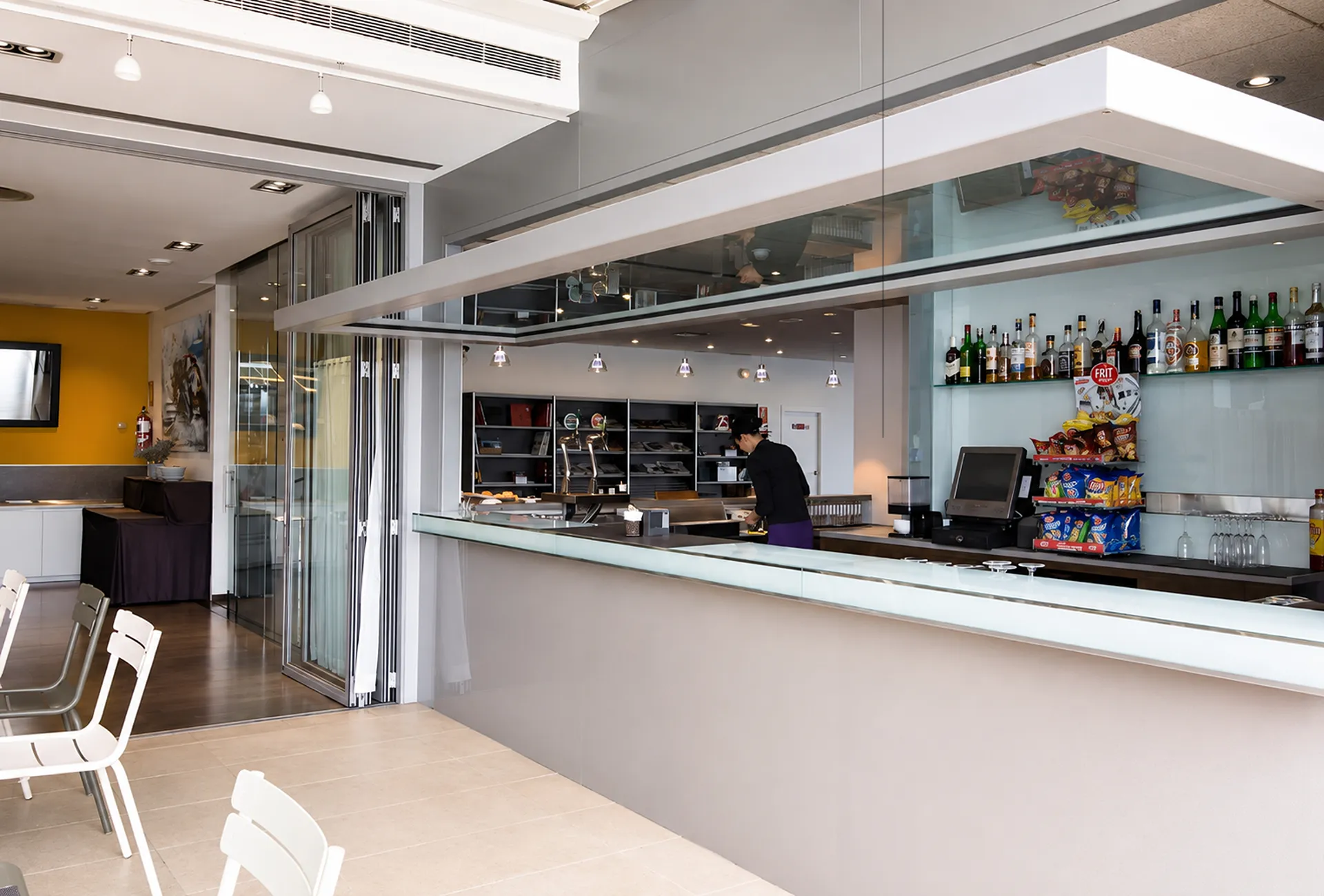 Interior de bar moderno con mostrador, bebidas y un cocinero trabajando