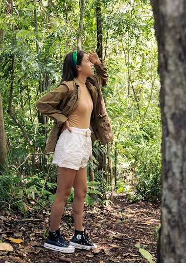 Mujer caminando entre la selva tropical, observando el entorno con naturaleza verde.
