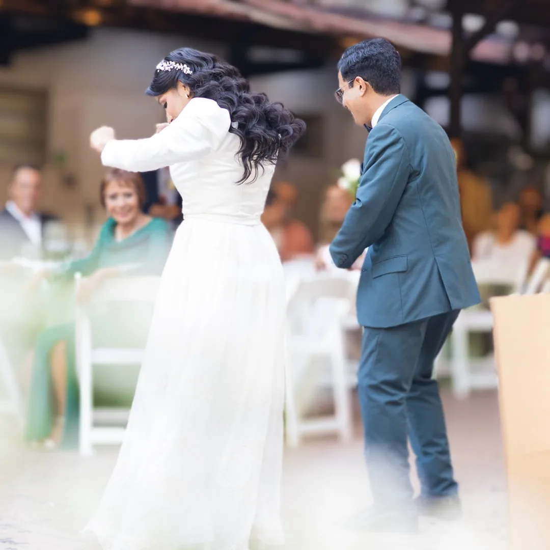 Novios bailando en la boda, ella con vestido blanco y &eacute;l con traje azul