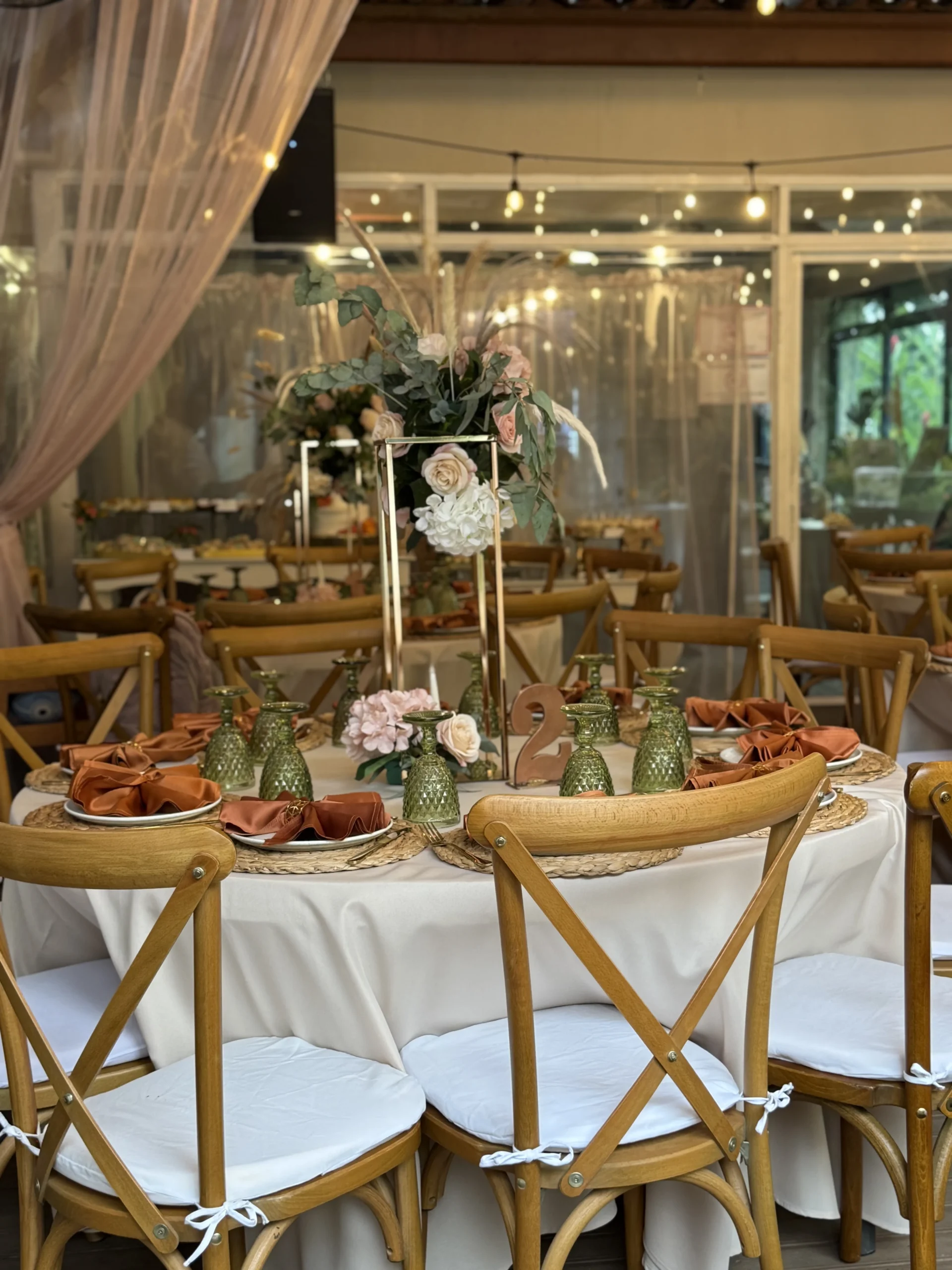 Mesa decorada con flores blancas y rosadas en un sal&oacute;n iluminado con luces colgantes