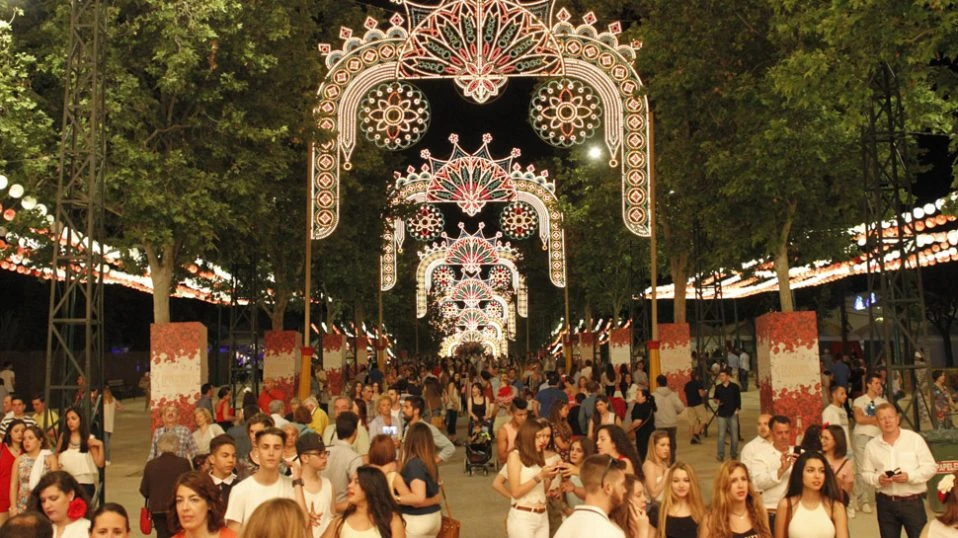 Arco de luces ornamentales y multitud paseando en una feria nocturna