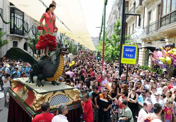 Multitud en desfile con carroza de dragón gigante y señal de taxi