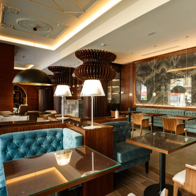 Interior de cafeter&iacute;a moderna con mesas, l&aacute;mparas y sof&aacute; color turquesa