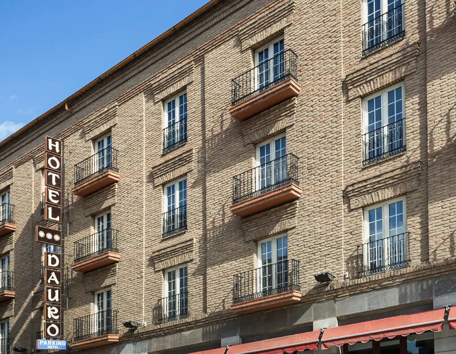 Fachada de hotel en edificio de ladrillo con balcones y cielo azul