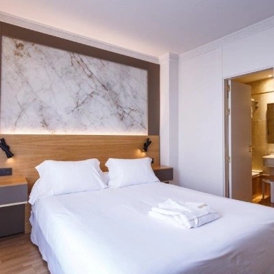 Dormitorio moderno con cama doble y pared de m&aacute;rmol gris.