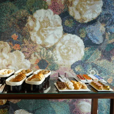 Buffet con boller&iacute;a y pasteles en bandejas sobre mesa de vidrio