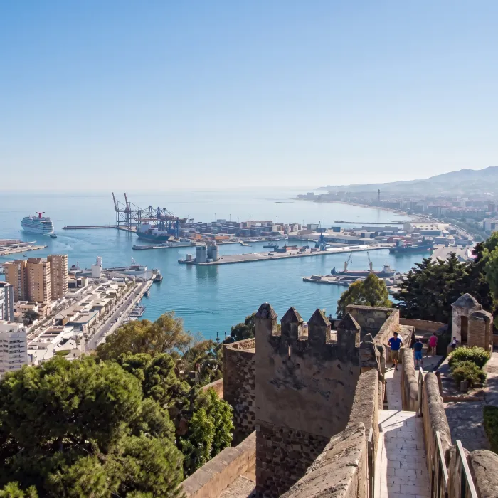 Vista del puerto y la bah&iacute;a desde las murallas, con barcos y gr&uacute;as.