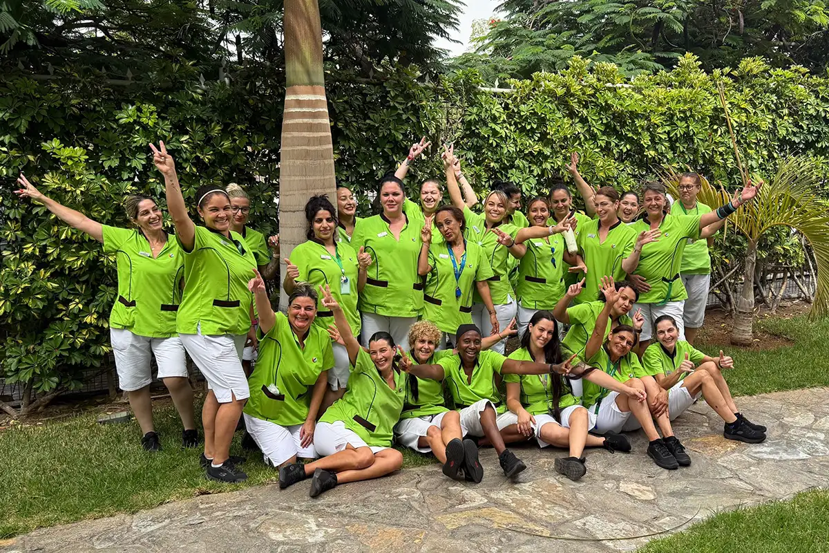 Equipo con chaquetas verdes celebrando con el pulgar arriba en un jardín