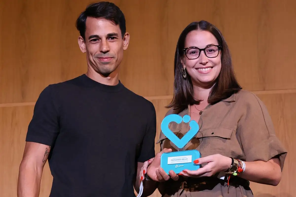 Pareja sonriente sosteniendo un premio con un corazón azul.