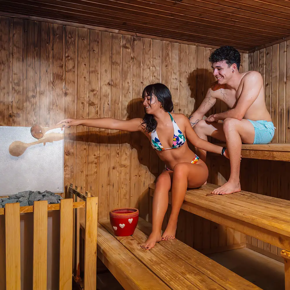 Pareja disfrutando de una sauna de madera, relaj&aacute;ndose junto a la sauna