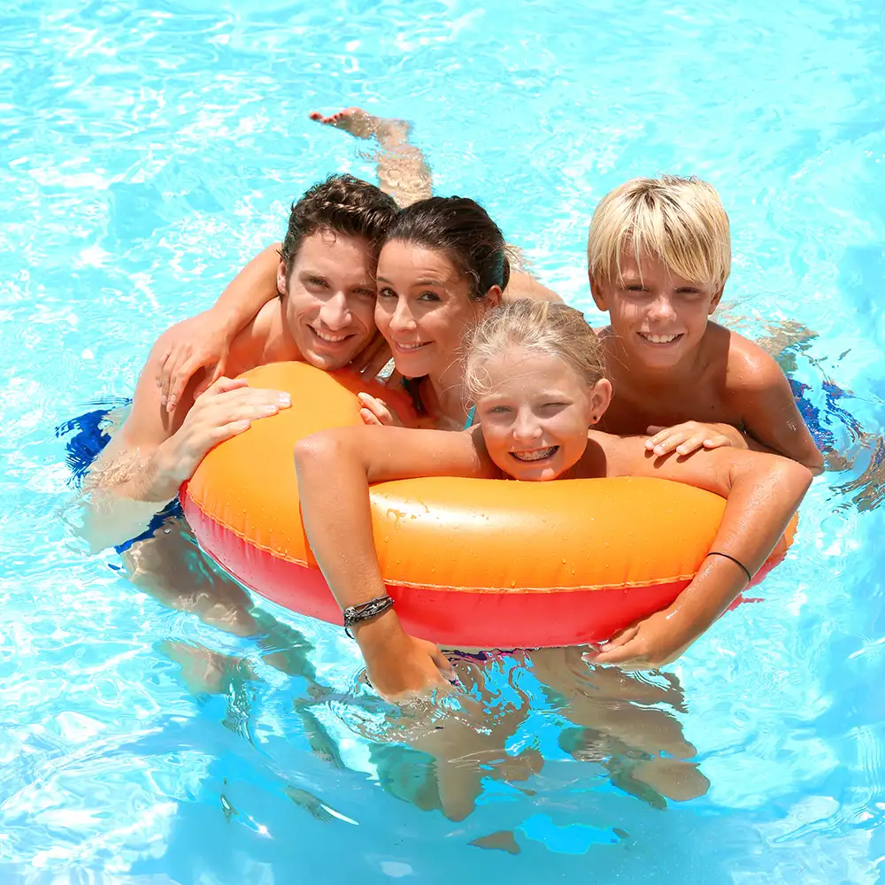 Familia sonriente en piscina con un flotador naranja y rojo