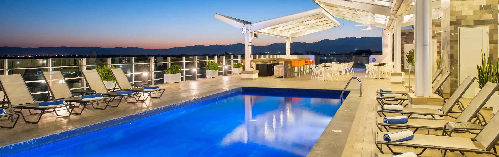 Terrace with swimming pool and sun loungers, sunset overlooking the mountains.