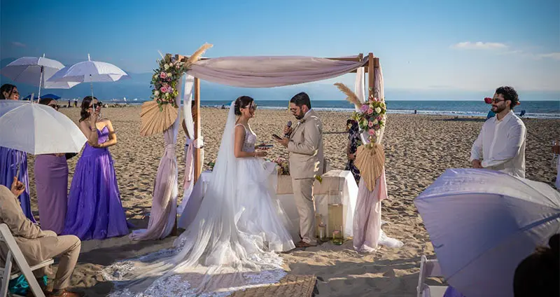 Beach wedding: couple with flower altar and ceremony by the sea.
