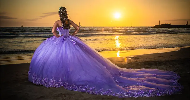 Woman in a lilac dress on the beach at sunset.