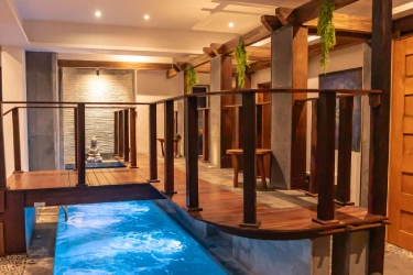 Indoor pool next to wooden columns and warm ambient light