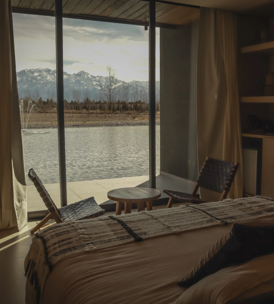 Habitaci&oacute;n con cama y vista al lago y monta&ntilde;as desde una ventana grande