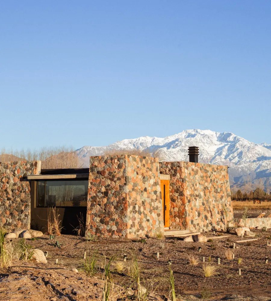 Casa de piedra con chimenea y monta&ntilde;as nevadas al fondo