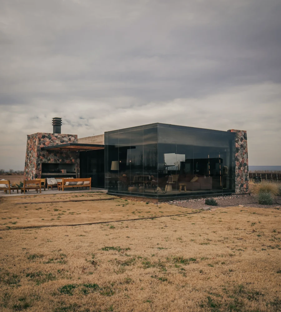 Casa moderna de vidrio con chimenea y patio al aire libre, cielo nublado