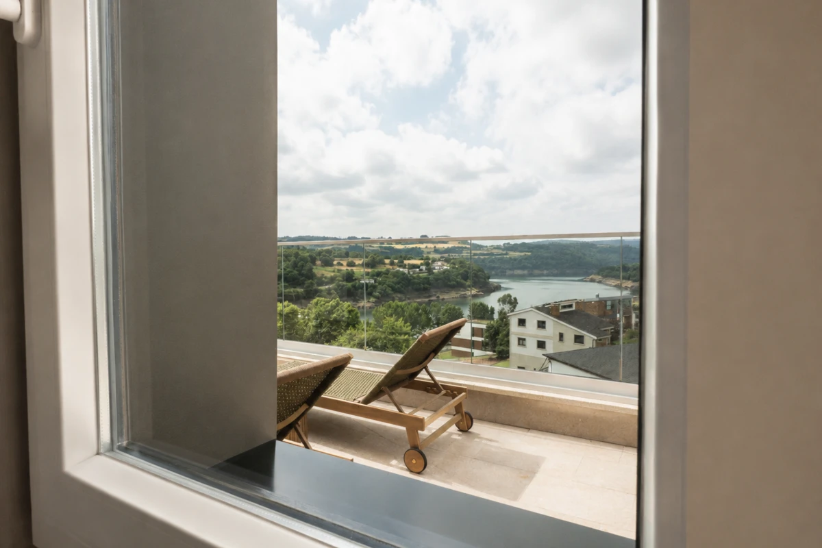 Silla reclinable en terraza con vista al r&iacute;o y campo desde una ventana